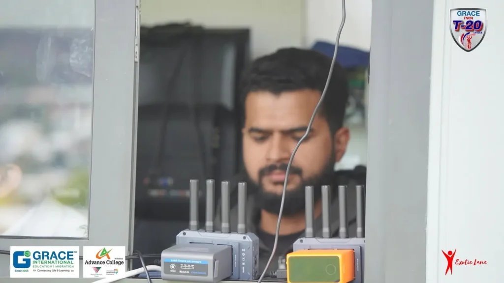 Crew member in the broadcast booth surrounded by streaming and wireless gear