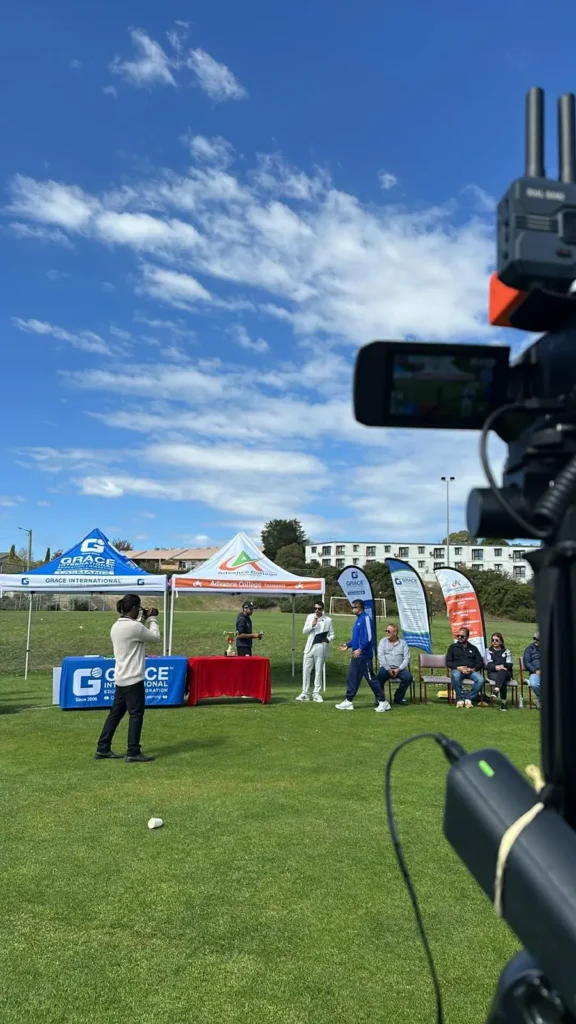 Camera in the foreground looking across a sunny ground with marquees