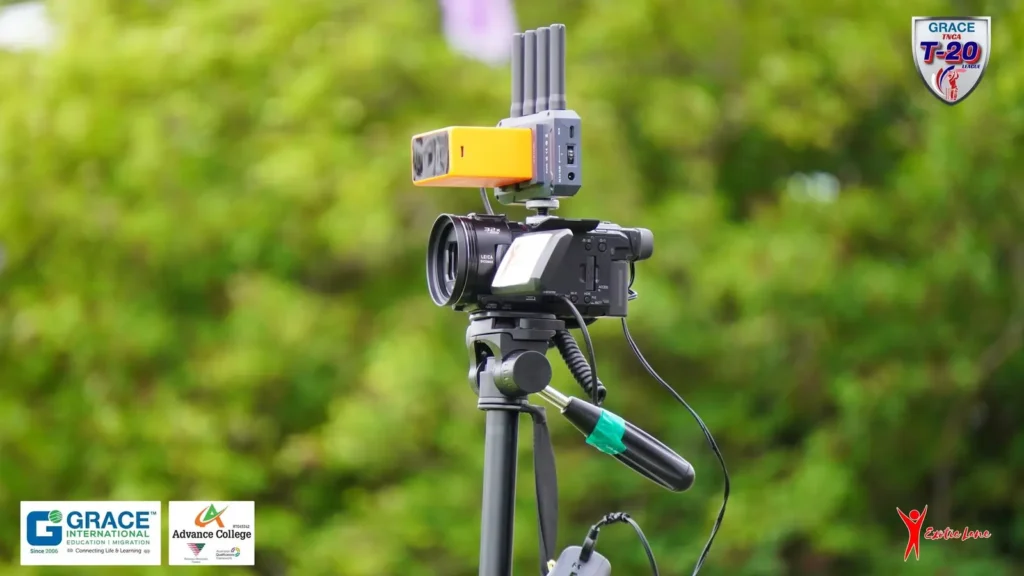 Camera with microphone mounted on a tripod at the boundary, trees behind