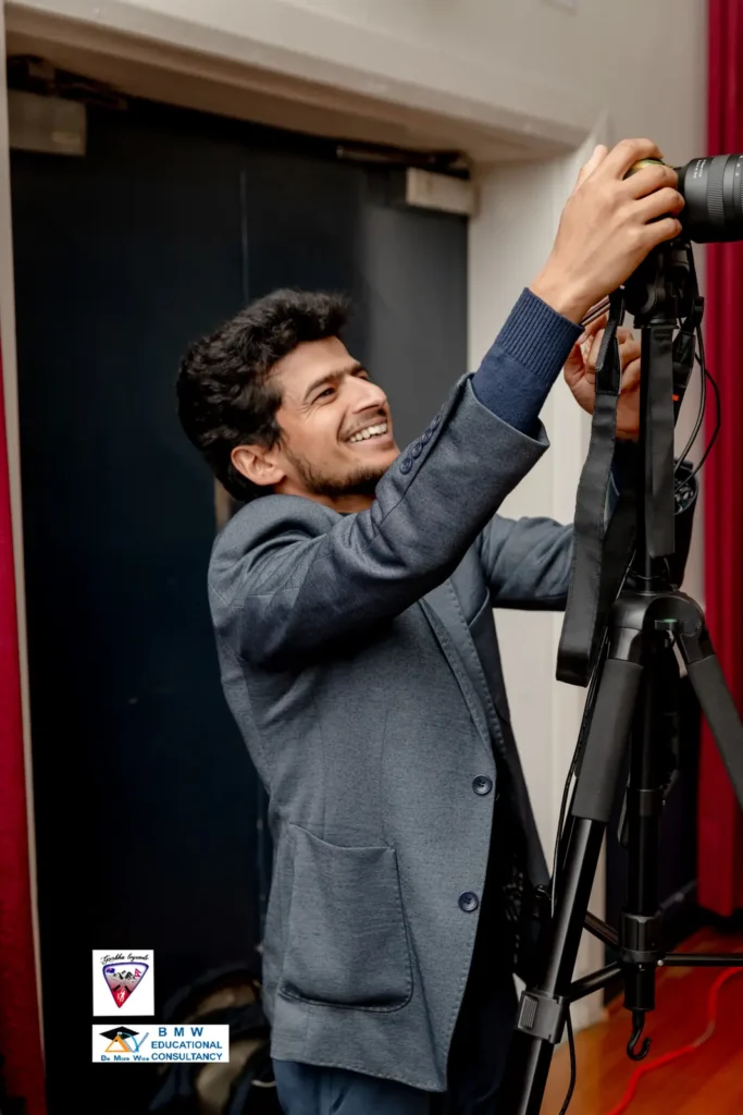 Camera operator smiling while adjusting a camera on a tall tripod