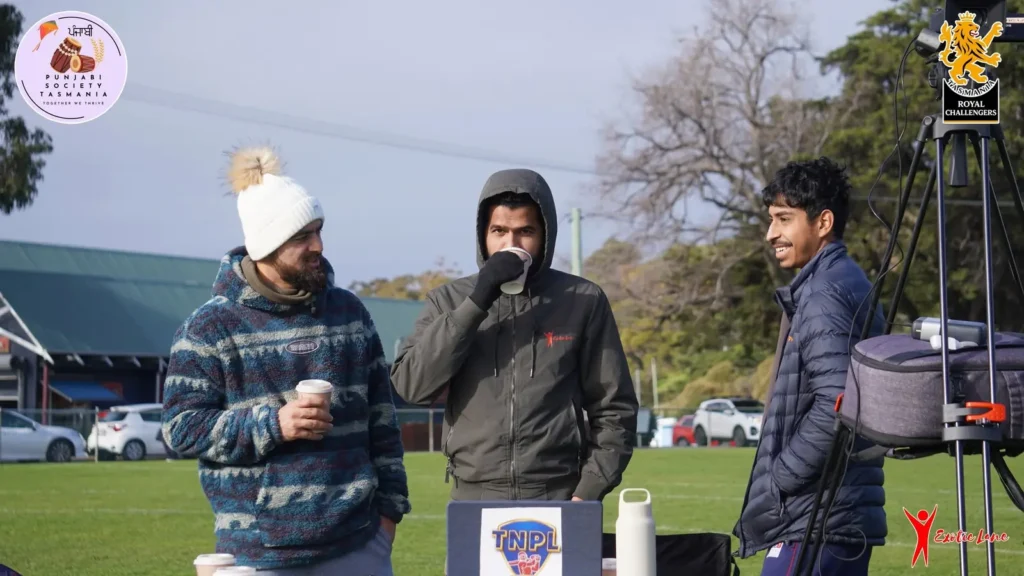 Three crew members in winter jackets with coffee beside the camera