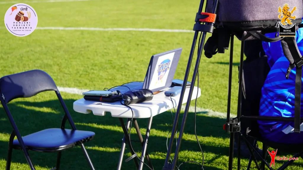 Laptop on a table beside a camera on a tripod on the grass