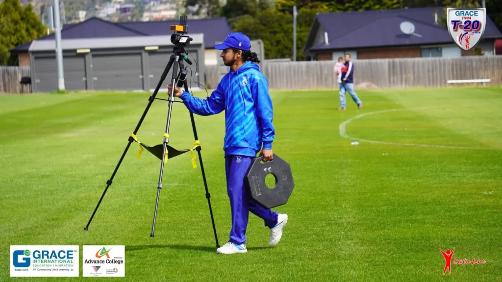 Crew member carrying a tripod and cable across the field before play